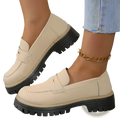 Cream-colored leather women’s platform loafers with black chunky soles and decorative toe strap for casual wear