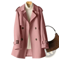 Women’s plus size soft pink double-breasted trench coat midi windbreaker with dark buttons and belt buckles over cream turtleneck
