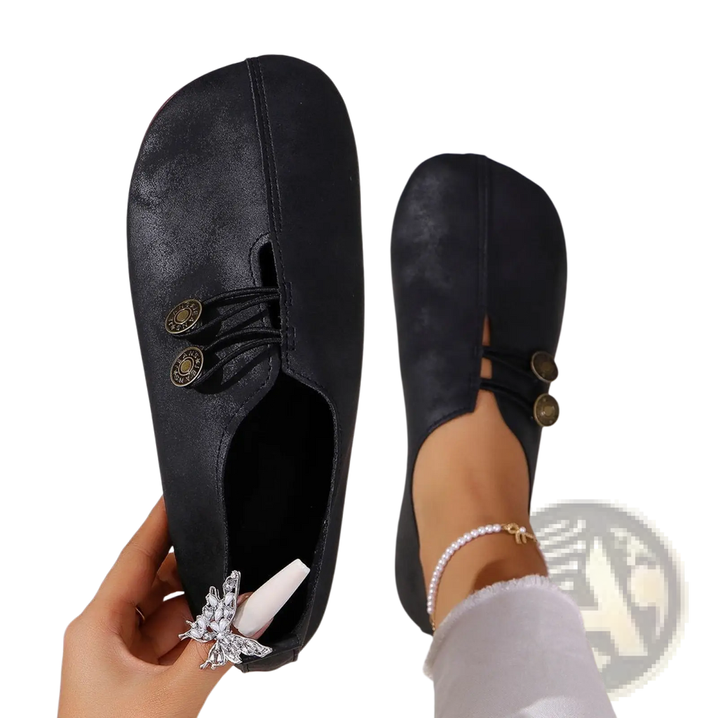 Women’s black leather slip-on shoes with gold-tone buttons and silver butterfly charm side detail