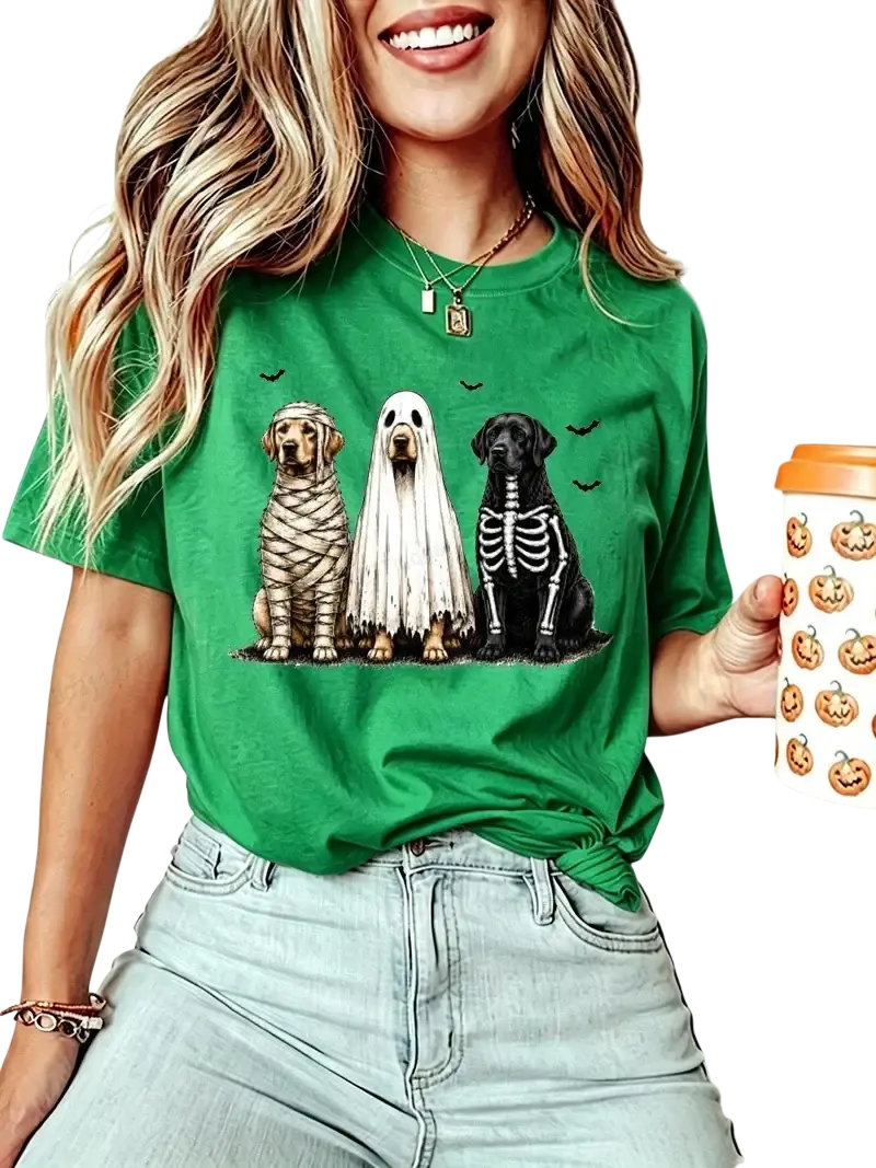 Green short sleeve women’s t-shirt featuring halloween graphic of three dogs dressed as mummy ghost and skeleton