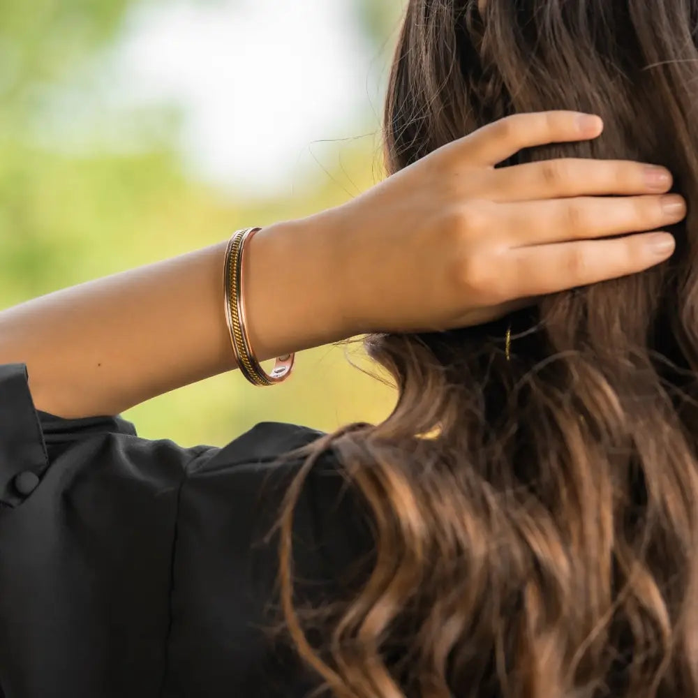 Rose gold twisted copper magnetic therapy bangle with textured braided design worn on wrist