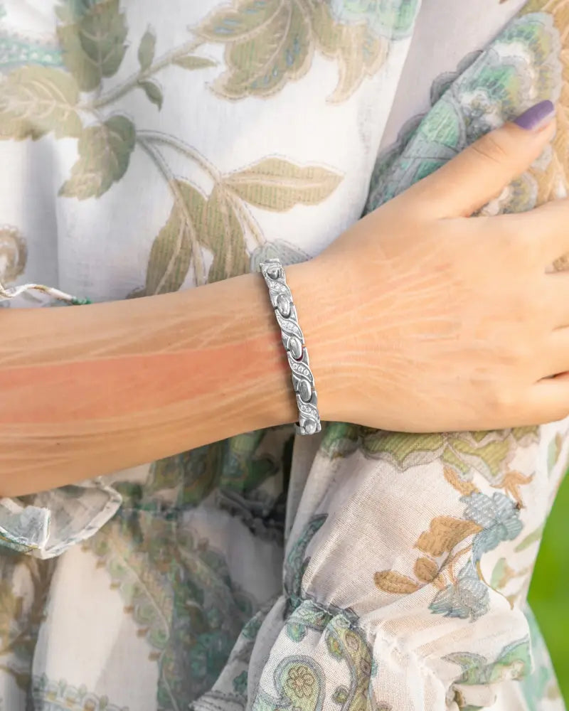 Women’s silver crystal xo neodymium magnetic bracelet with an intricate twisted design worn on a wrist