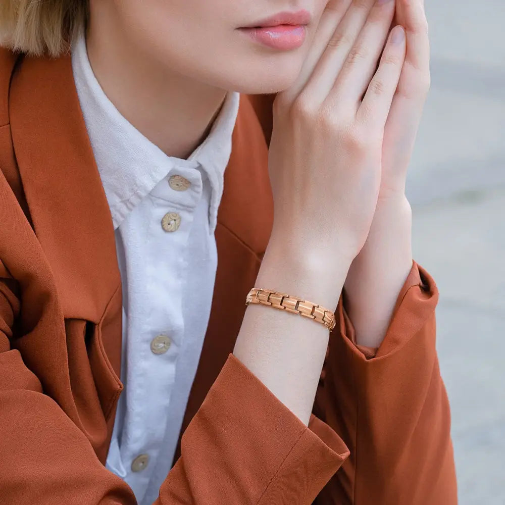 A sleek rose gold titanium magnetic therapy bracelet with segmented interlocking metal design worn on the wrist