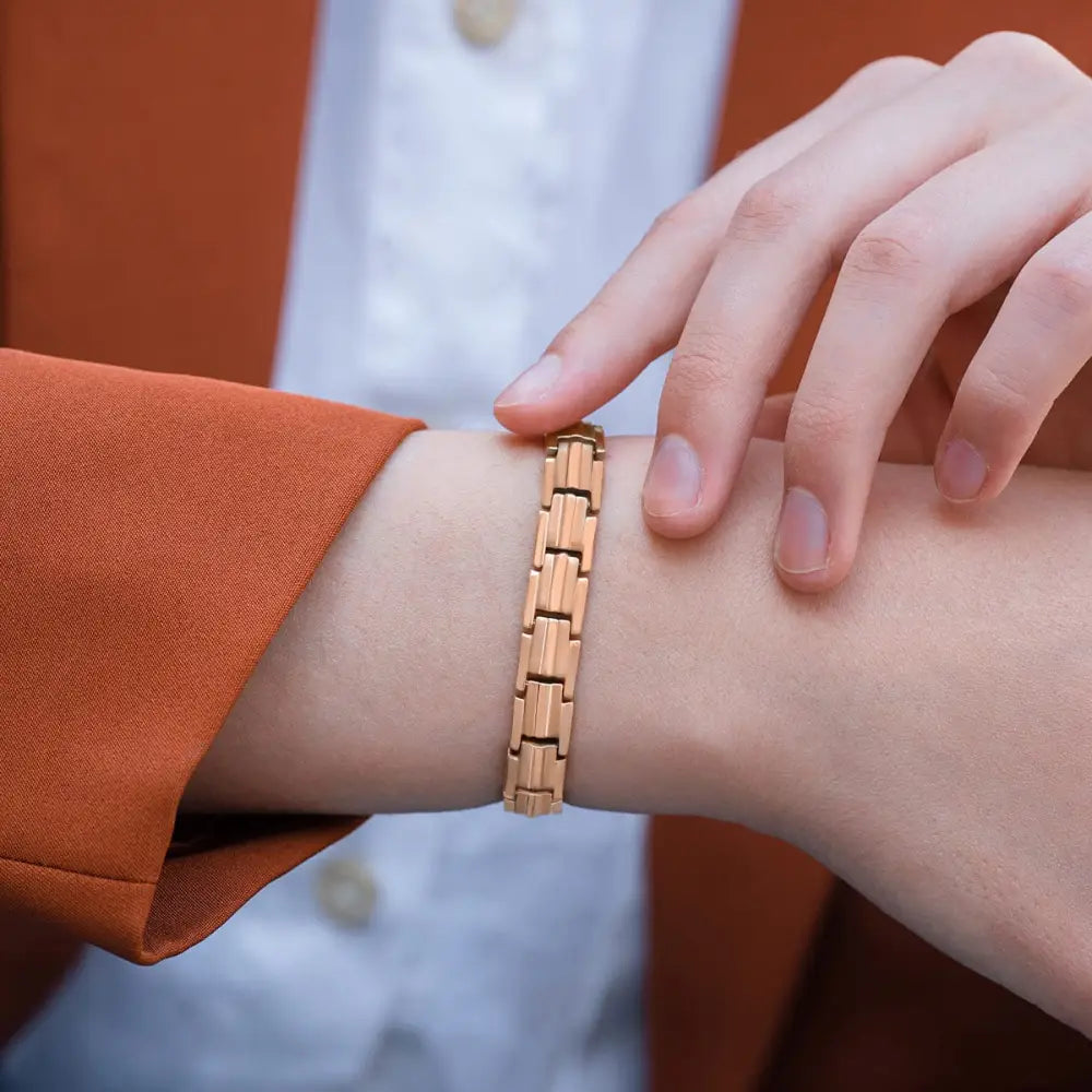A sleek rose gold titanium magnetic therapy bracelet with modern interlocking links worn on a wrist