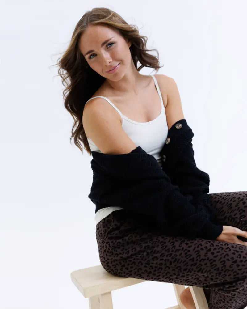 Woman wearing a white wonder cami cotton stretch layering tank top with black leopard print pants and an open black cardigan