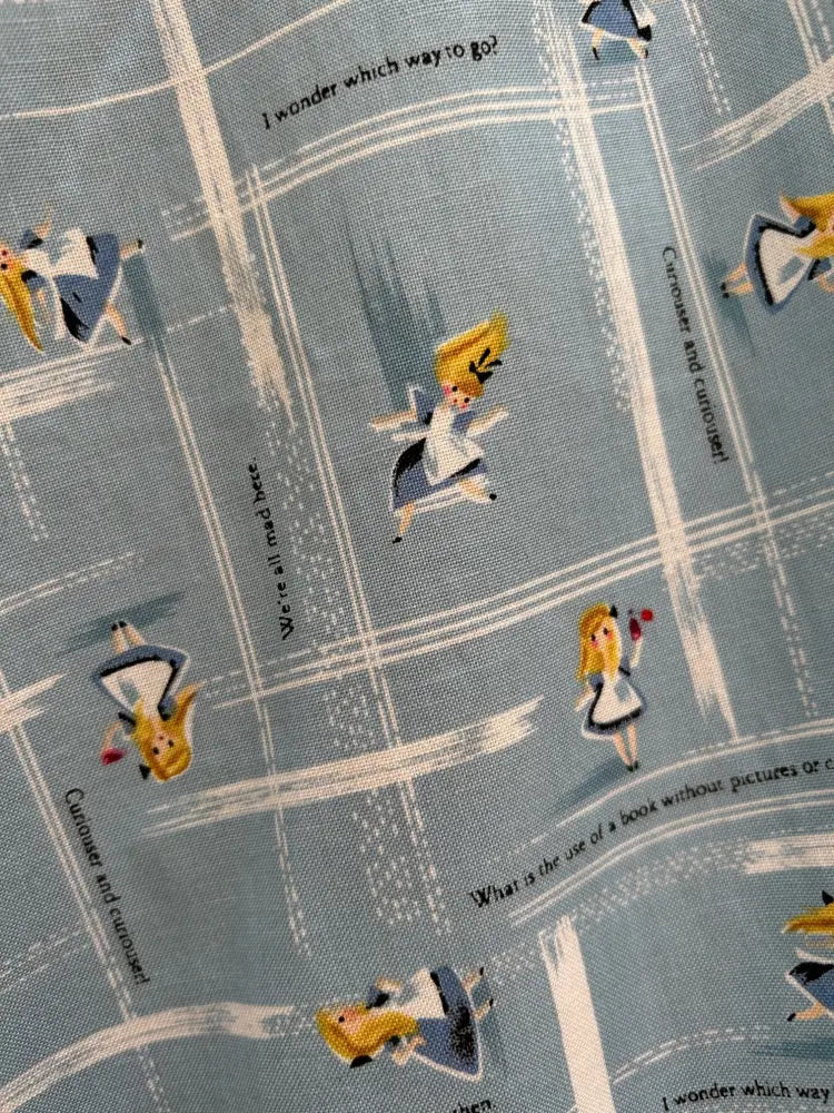 Alice in wonderland light blue pleated skater skirt with fabric featuring repeating characters and quotes from the book