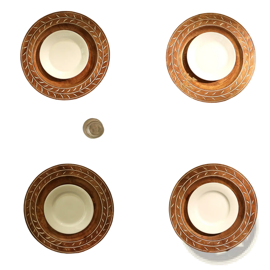 Set of four handcrafted 13 inch wooden charger plates with intricate leaf-patterned borders holding white ceramic bowls