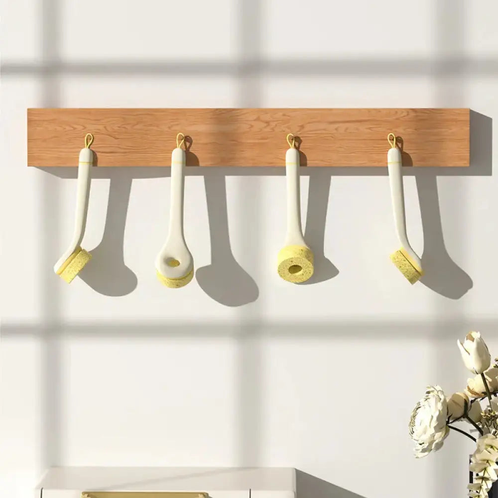 Four eco friendly wood pulp kitchen scrub brushes with white and yellow sponge heads and wooden handles hanging on rack