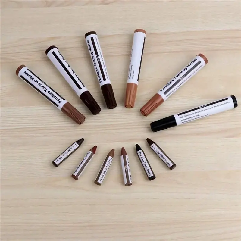 Wood repair kit with markers and wax sticks includes six brown touch-up markers and five matching filler sticks on wood surface