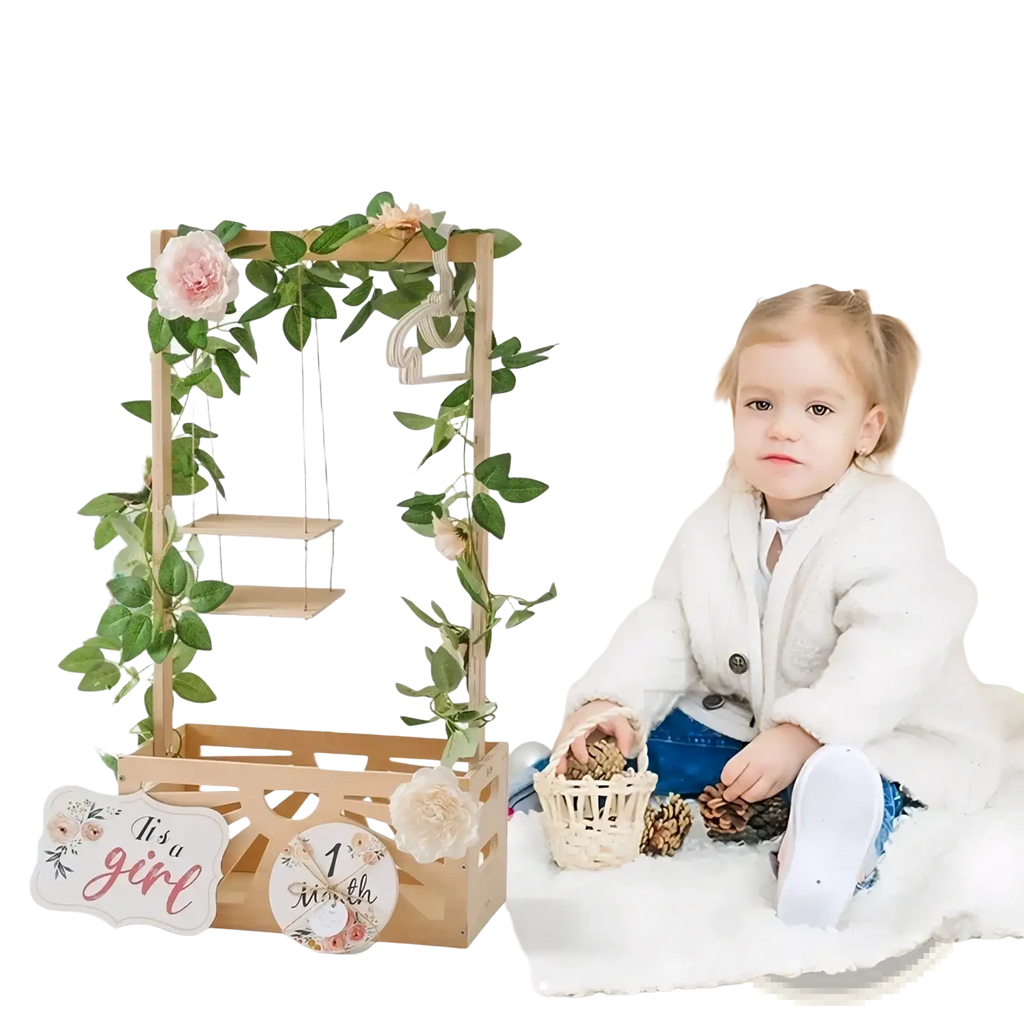 Wooden baby storage basket nursery decor with a wooden arch decorated with greenery pink flowers and a its a girl sign