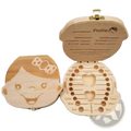 Light-colored wooden baby tooth storage box with smiling face design and labeled slots for tooth keepsake organization