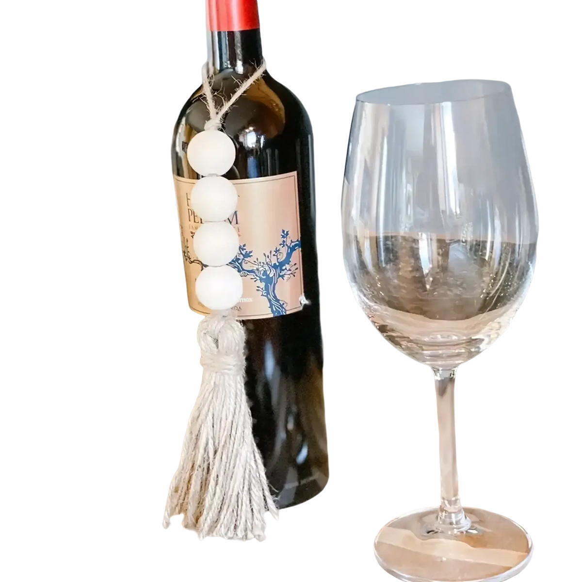 A dark glass wine bottle decorated with a white wooden bead garland tassel ornament charm