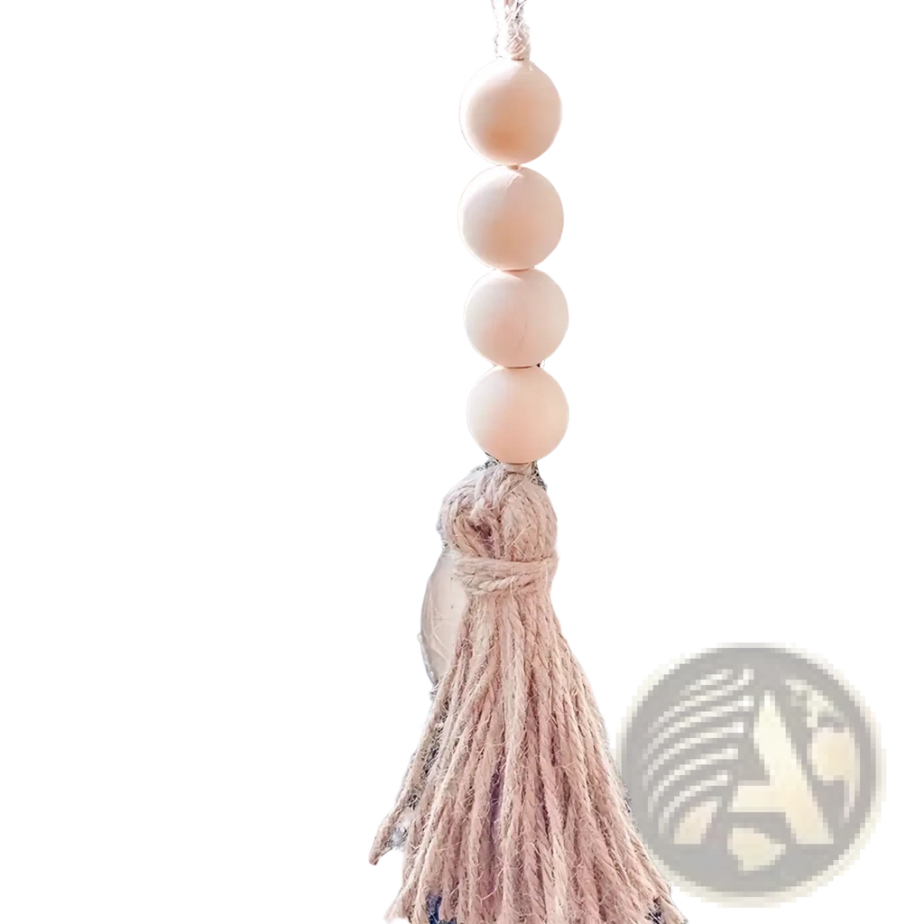 A delicate beige wooden bead garland tassel ornament hanging from frosted pine branches