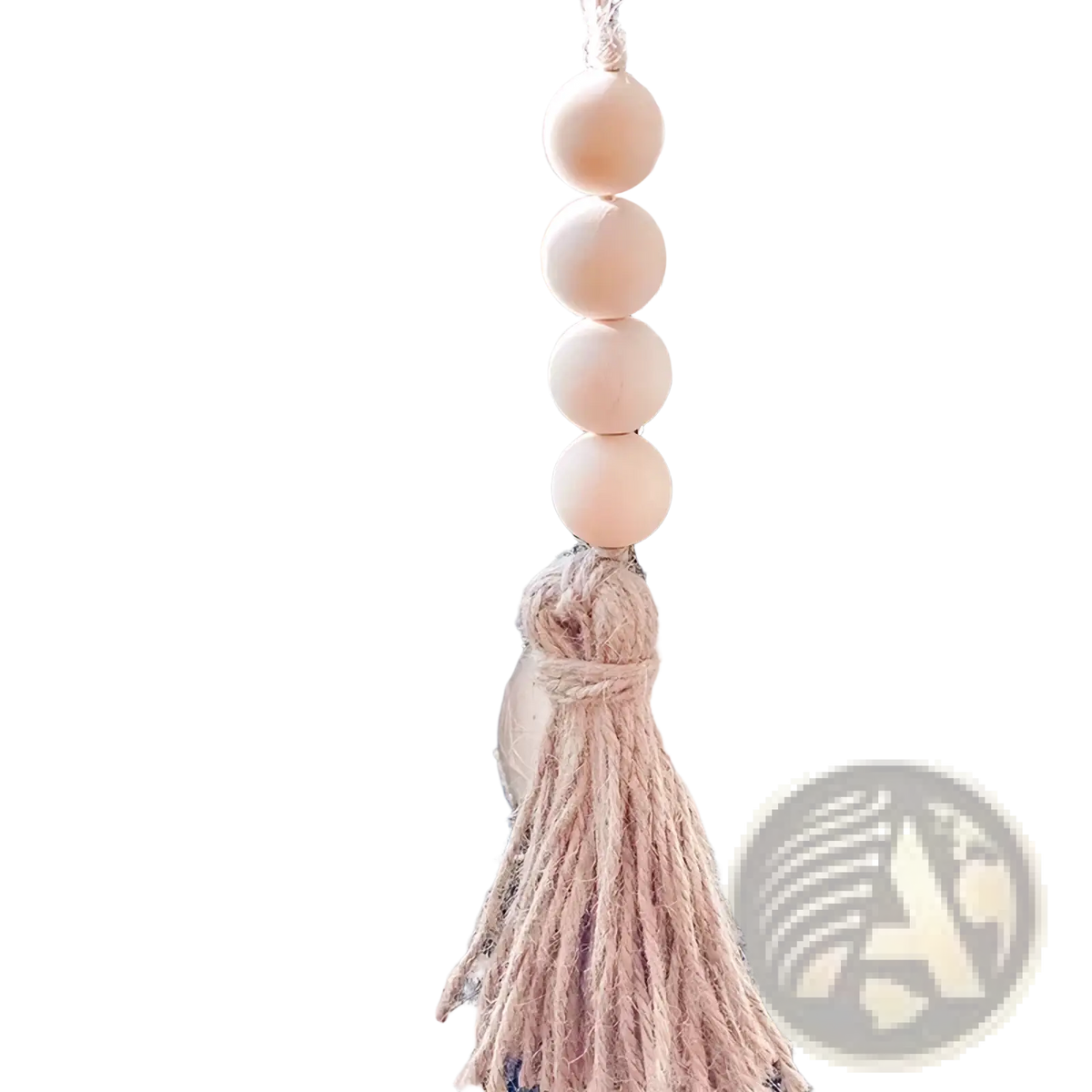 A delicate beige wooden bead garland tassel ornament hanging from frosted pine branches
