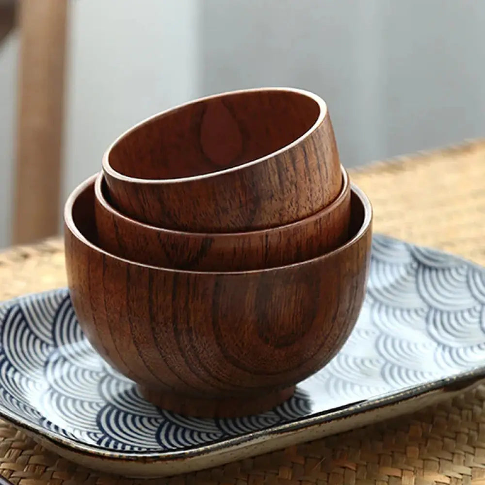 Set of three nested handcrafted Japanese style natural wooden bowls with warm brown finish and visible wood grain
