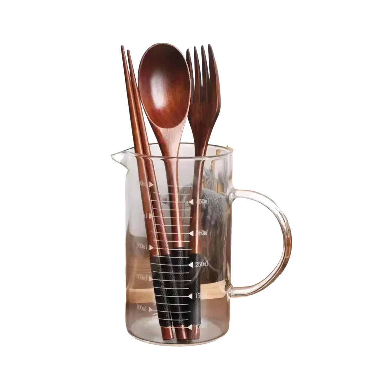 Wooden cutlery set with fork spoon and chopsticks in a clear glass measuring cup with black measurement markings