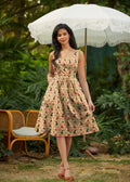 A woman wearing a woodland scout vintage cotton fit and flare dress in beige floral print with green and red accents