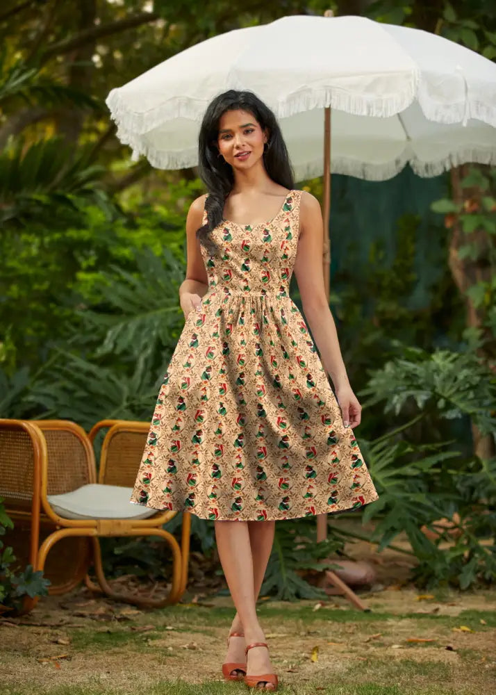 A woman wearing a woodland scout vintage cotton fit and flare dress in beige floral print with green and red accents