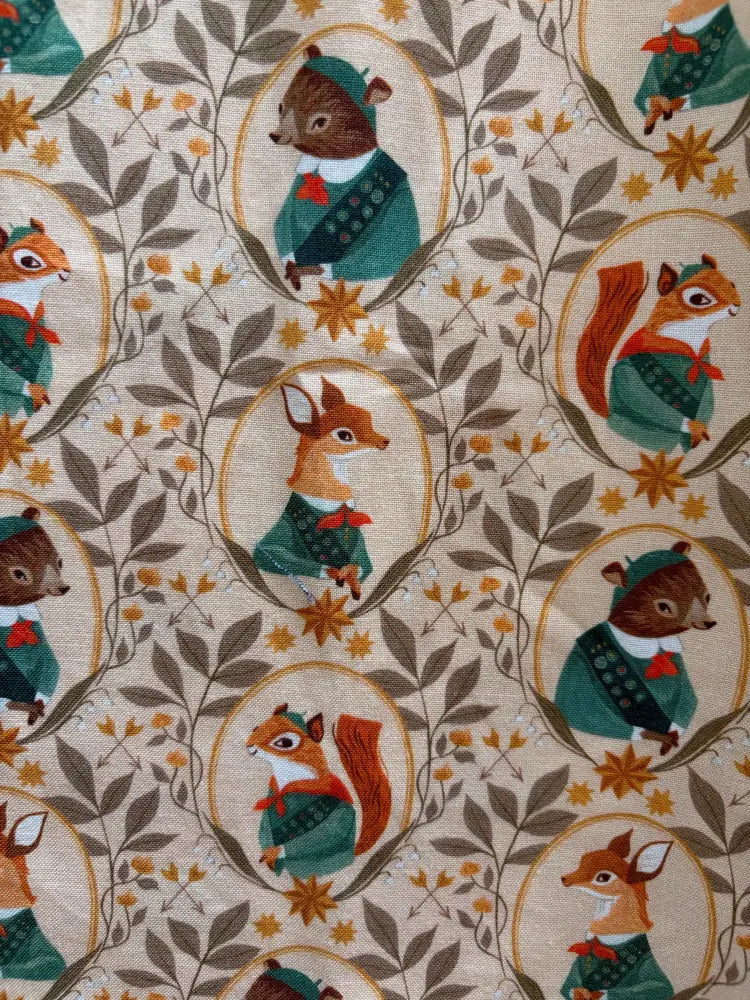 Beige vintage cotton fit and flare dress with woodland animals in teal and brown framed by golden oval borders