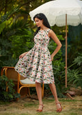 A woman wears a sleeveless woodland vintage cream cotton a-line dress with pockets and a pink green skull pattern