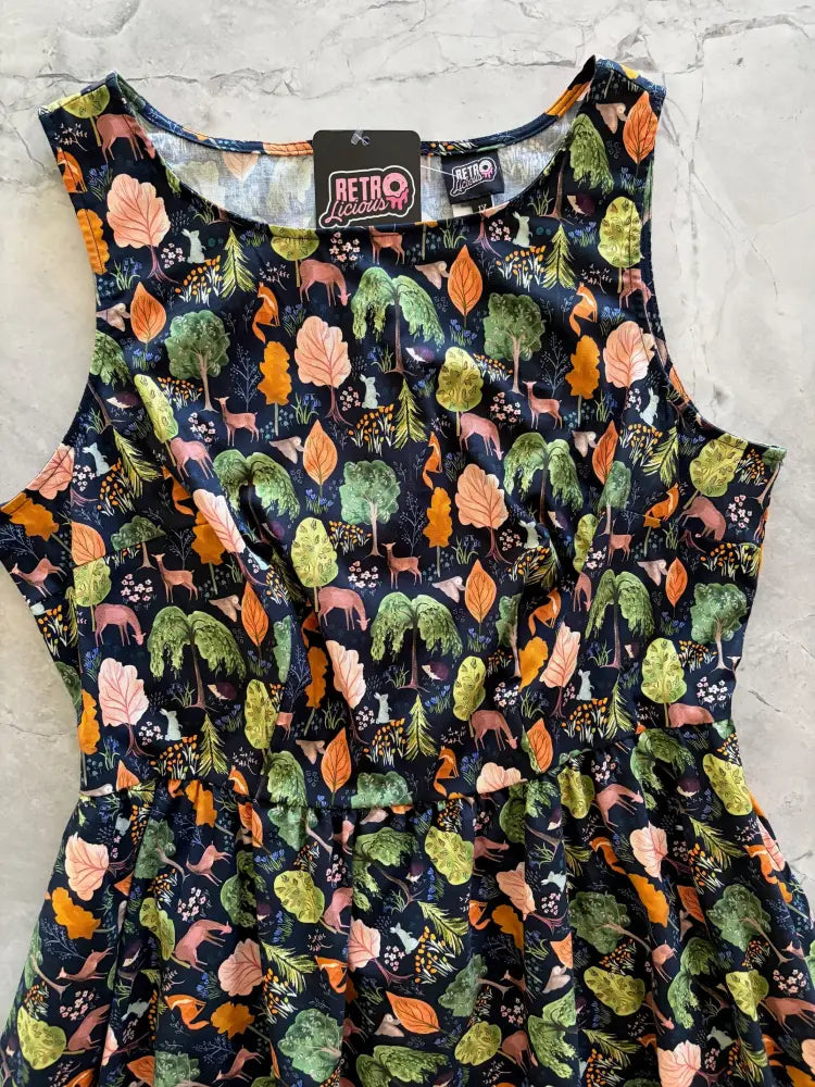 A sleeveless navy blue cotton 1950s vintage dress with vibrant woodland pattern including trees, deer, and foxes