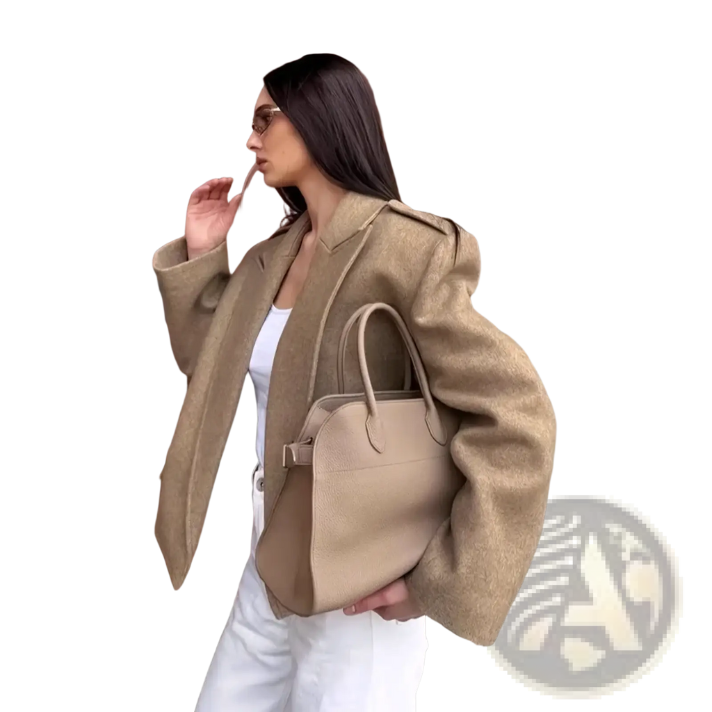 Beige leather handbag with structured shape and top handles paired with a wool blend winter coat