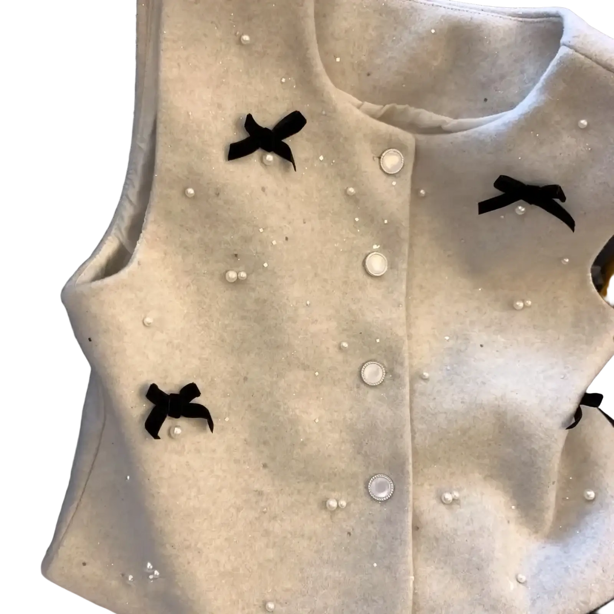 A soft off-white wool bow vest with black velvet bows and pearl button embellishments for elegant outerwear