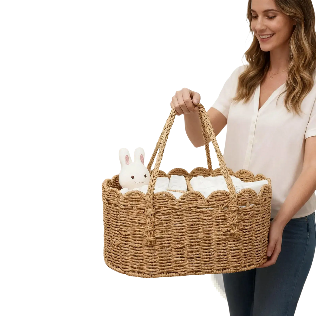 Woven diaper caddy made of natural wicker with scalloped edges and handles holding white baby items