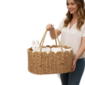 Woven diaper caddy made of natural wicker with scalloped edges and handles holding white baby items