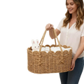 Woven diaper caddy made of natural wicker with scalloped edges and handles holding white baby items