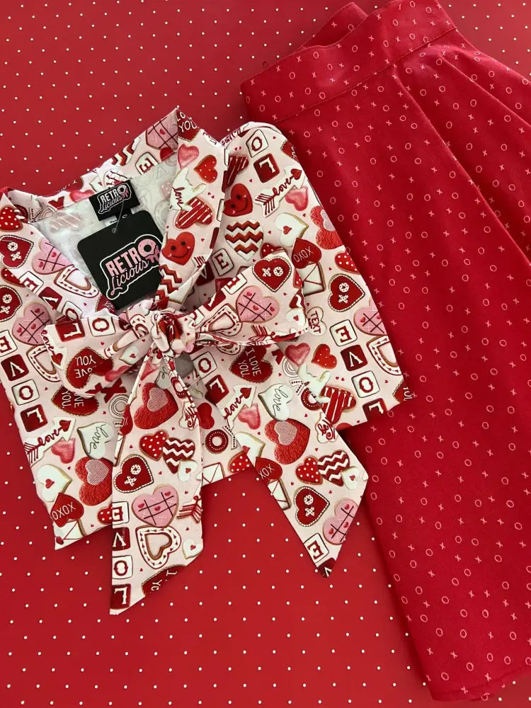 Red and white patterned 1950s vintage sleeveless cotton blouse with large bow neckline featuring valentine motifs