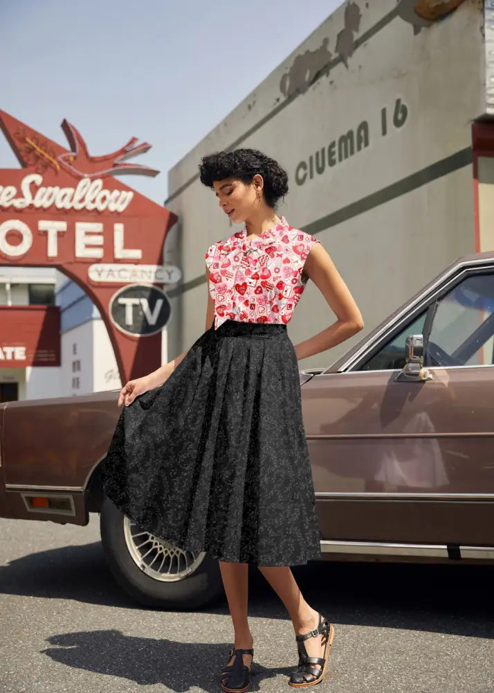 Black lace midi skirt with flared silhouette and floral pattern paired with xoxo print vintage 1950s bow neck cotton top