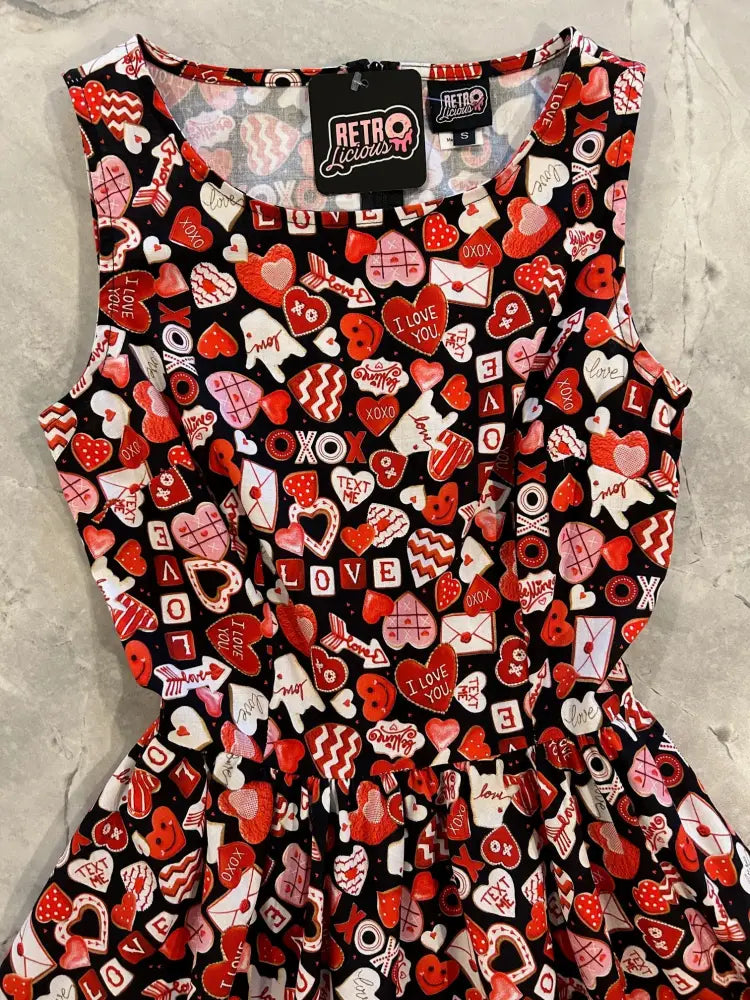 A black sleeveless vintage 1950s cotton dress with vibrant red pink and white heart and love letter print