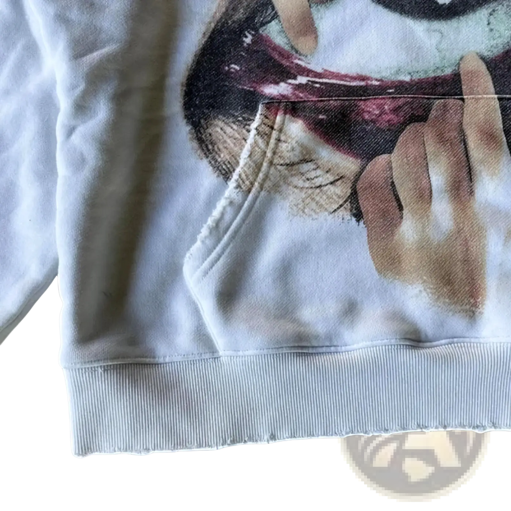 White oversized hoodie featuring a detailed graphic print of a hand holding a face with dark lips and muted skin tones