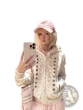 A cream-colored y2k star print zip hoodie with a lace-up front featuring metallic buttons and small star patterns