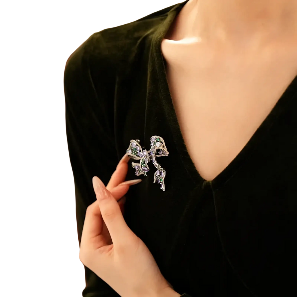 A sparkling silver zircon butterfly brooch with green and clear crystals pinned to a dark velvet top