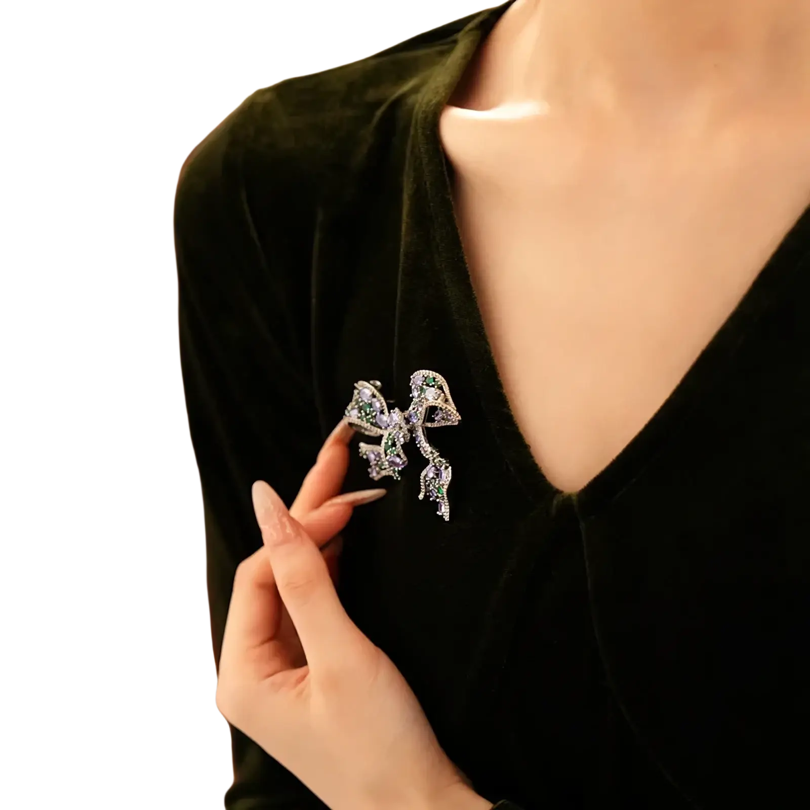 A sparkling silver zircon butterfly brooch with green and clear crystals pinned to a dark velvet top