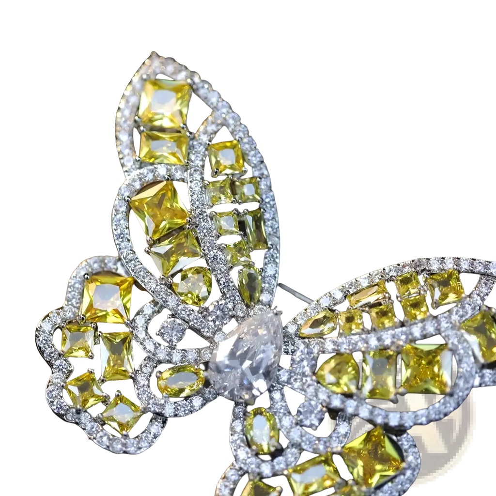 A zircon butterfly brooch with vibrant yellow and clear gemstones set in a silver-toned metal frame